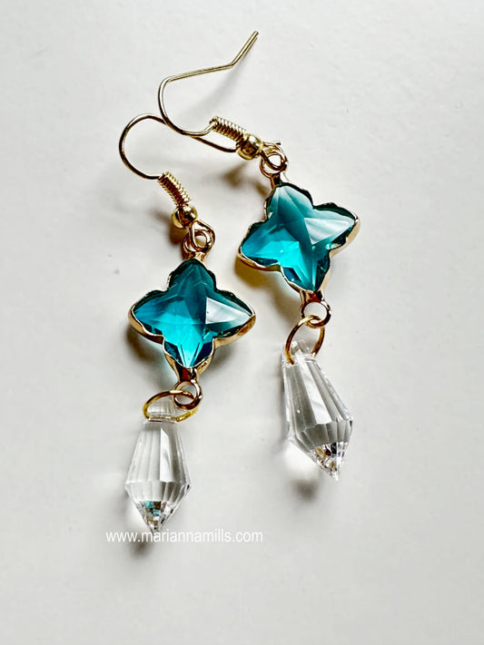 Celestial collection. One of a kind earrings, they can't be duplicated.  Designed and handmade by Marianna Mills.  Size: just a little over 2 inches  Teal blue glass star with metal outlining and clear crystal drop.